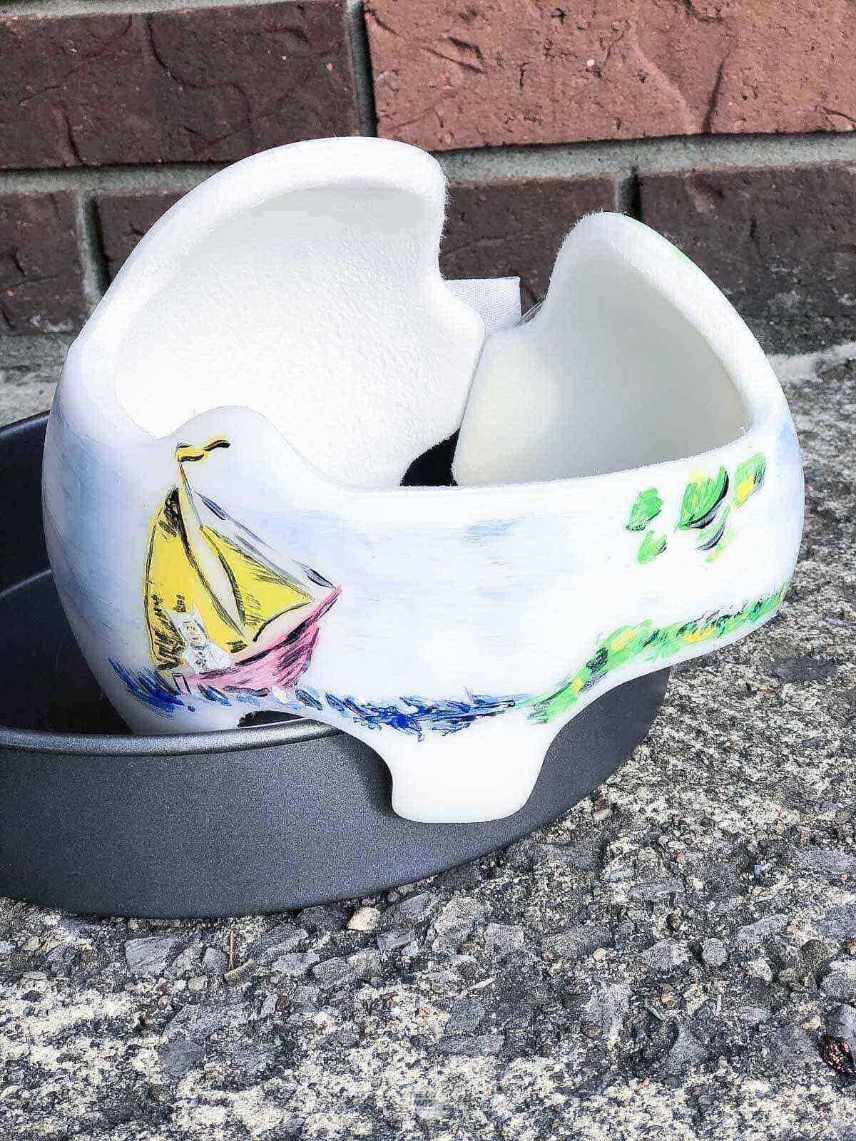baby helmet with painted boat and sky design in baking pan drying.