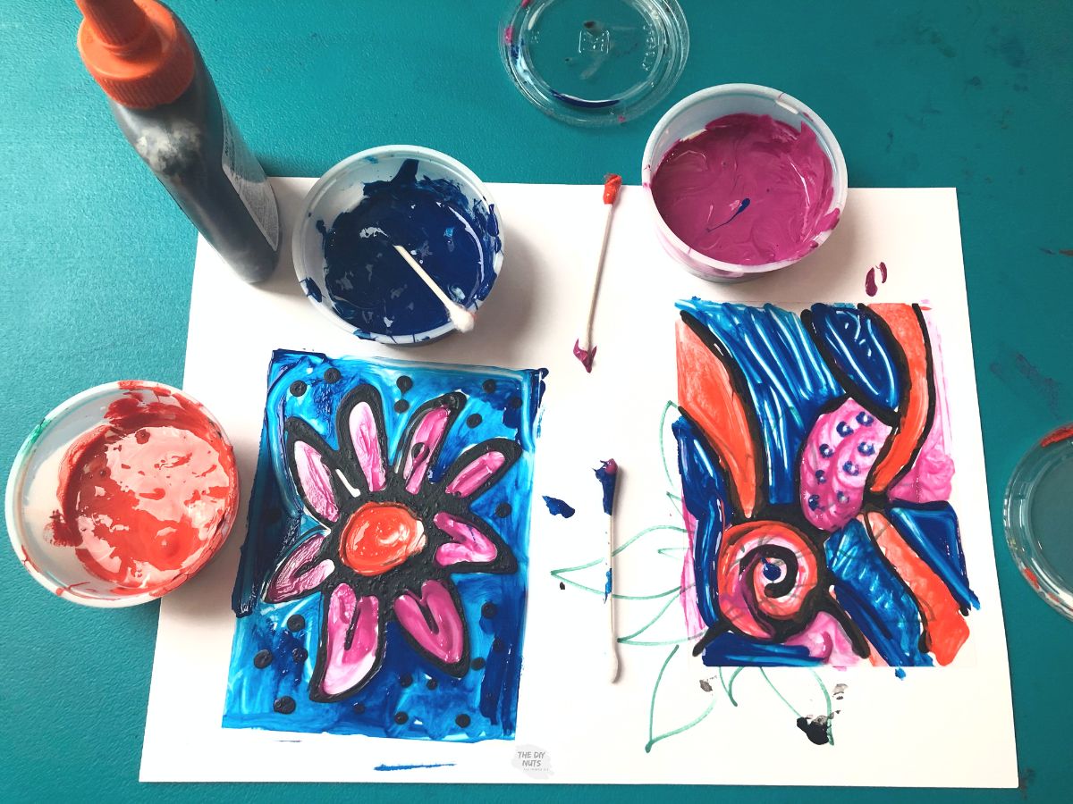 two finished stained glass crafts with orange, pink and blue paint.
