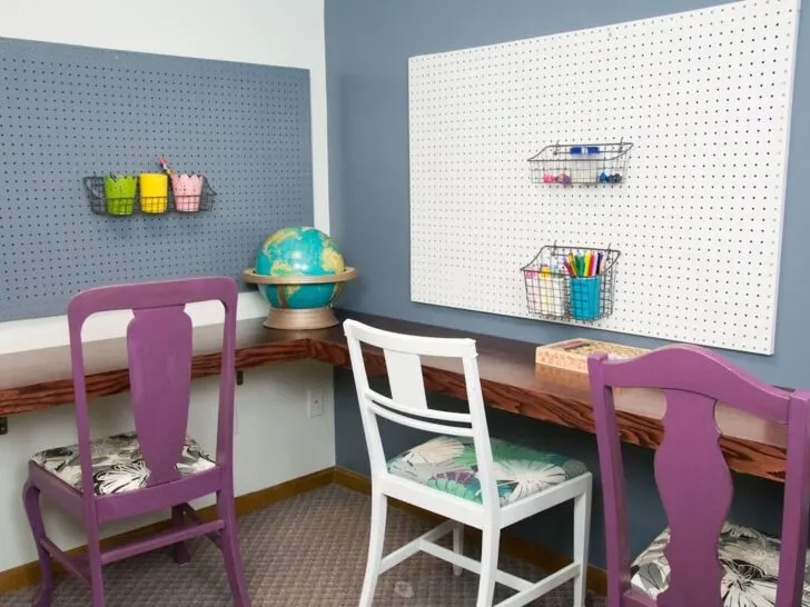 corner desk with 3 chairs and pegboards on the wall.