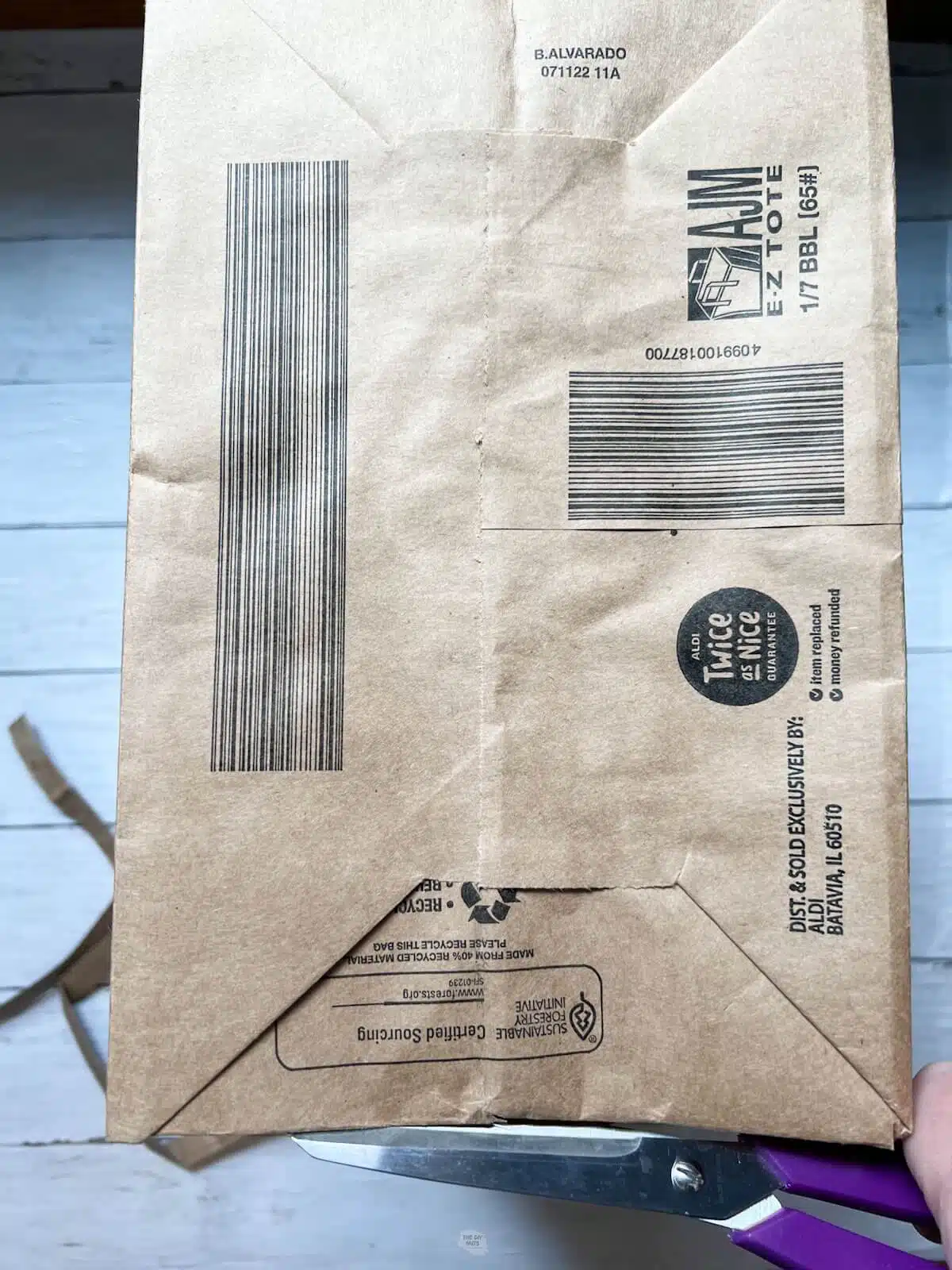 scissors cutting around bottom of brown bag.