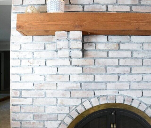 whitewash brick fireplace with wooden mantel.