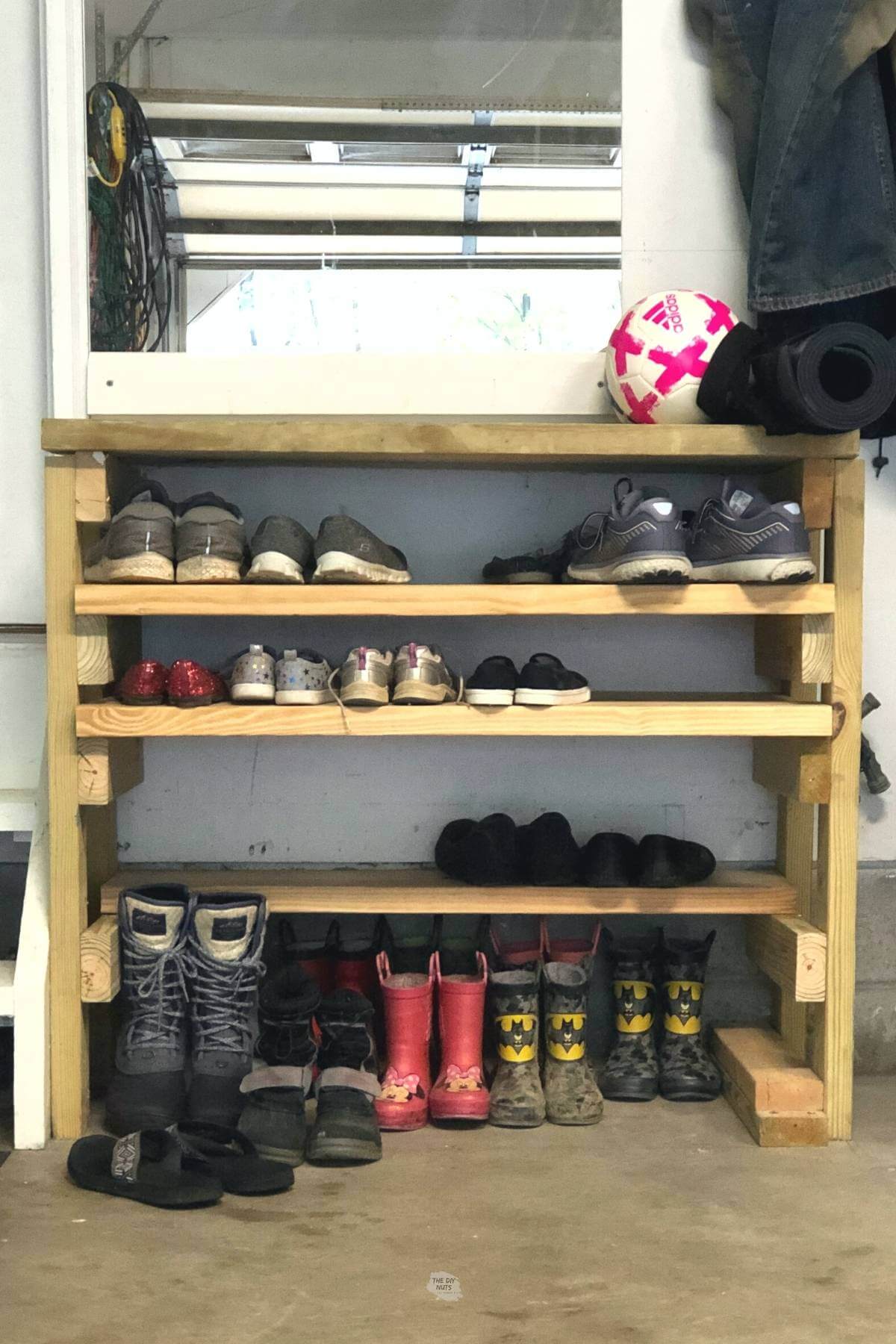 DIY wood shoe organizer with shoes and boots in garage.
