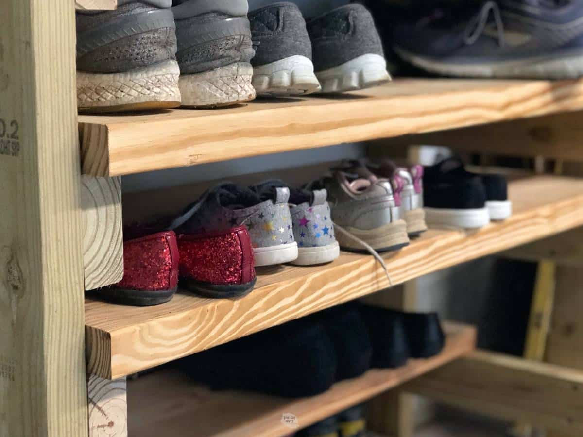 wooden shoe rack in garage with different shoes on it.
