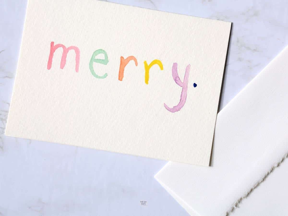 merry spelled on white card with part of envelope showing.