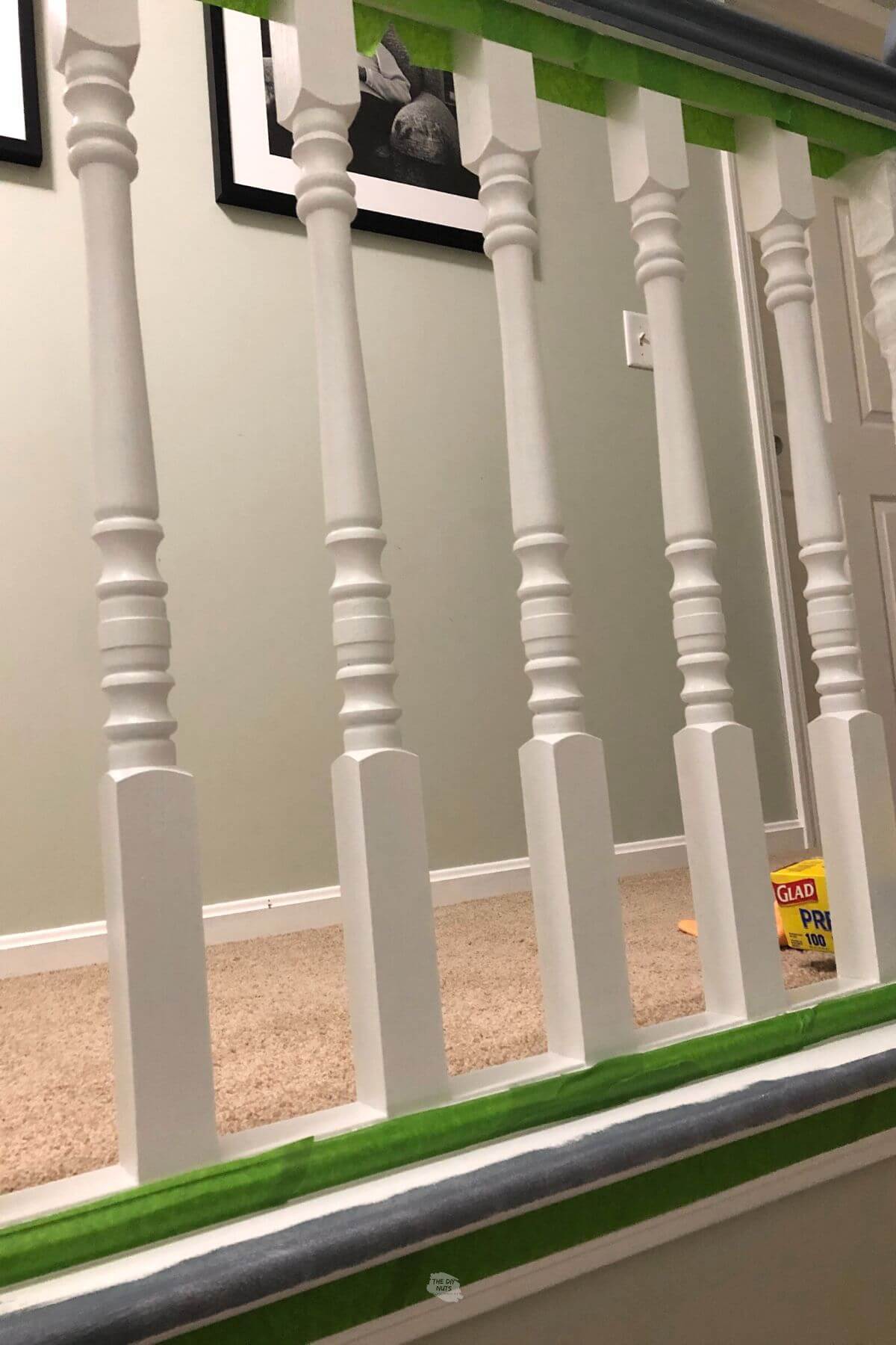 white painted stair spindles with green painter's tape.