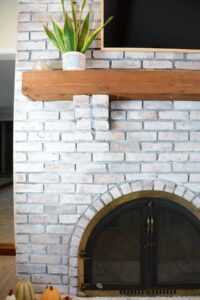 whitewashed brick fireplace with oak mantel.
