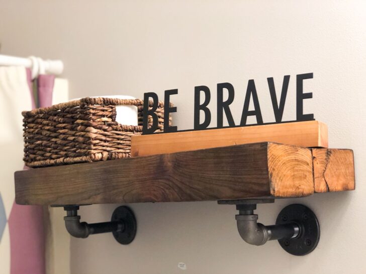 bathroom shelf made from reclaimed wood and pipes with be brave sign.