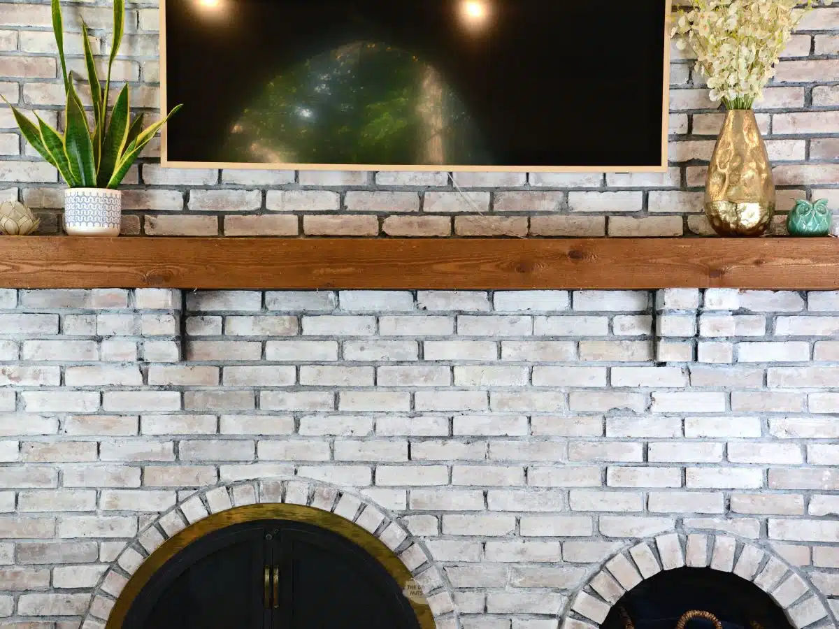 wood fireplace mantel with whitewashed brick.