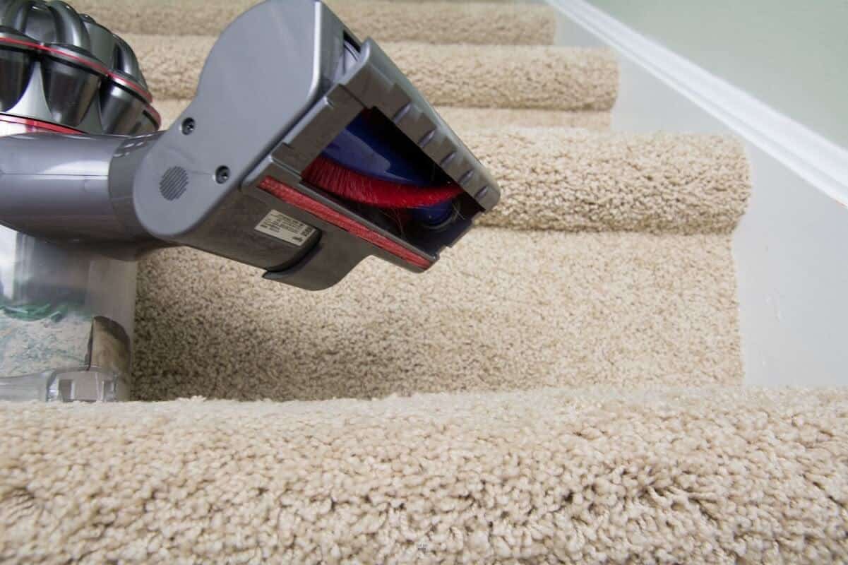 carpet attachement on handheld Dyson vacuum on steps.