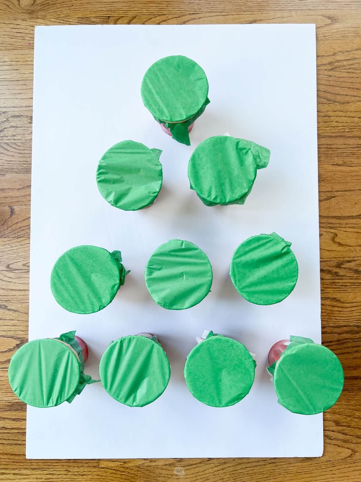 green tissue paper on cups in triangle shape on white foam core.