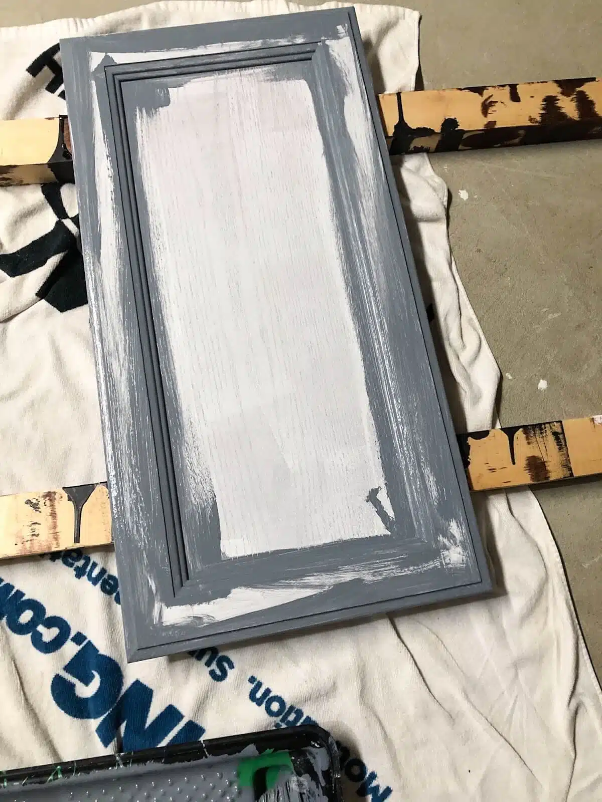 Using a paint brush to add gray latex enamel paint to cabinet door.