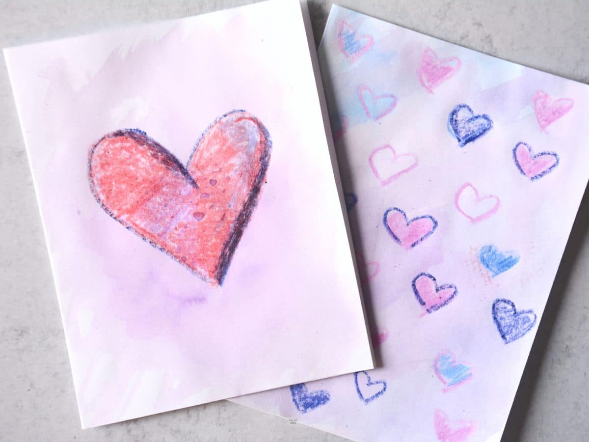 two heart cards drawn with crayons with watercolor painted on top.