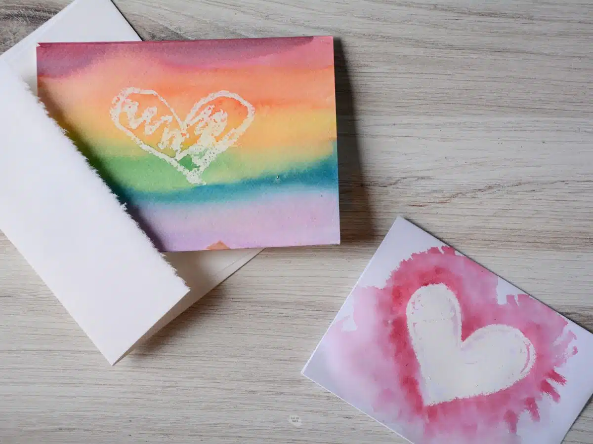 two DIY watercolor Valentine's day cards on wood table.