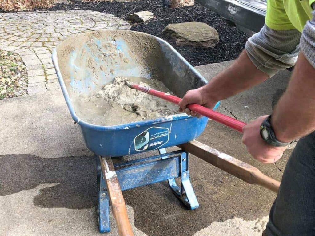 man mixing concrete in blue wheelbarrow.