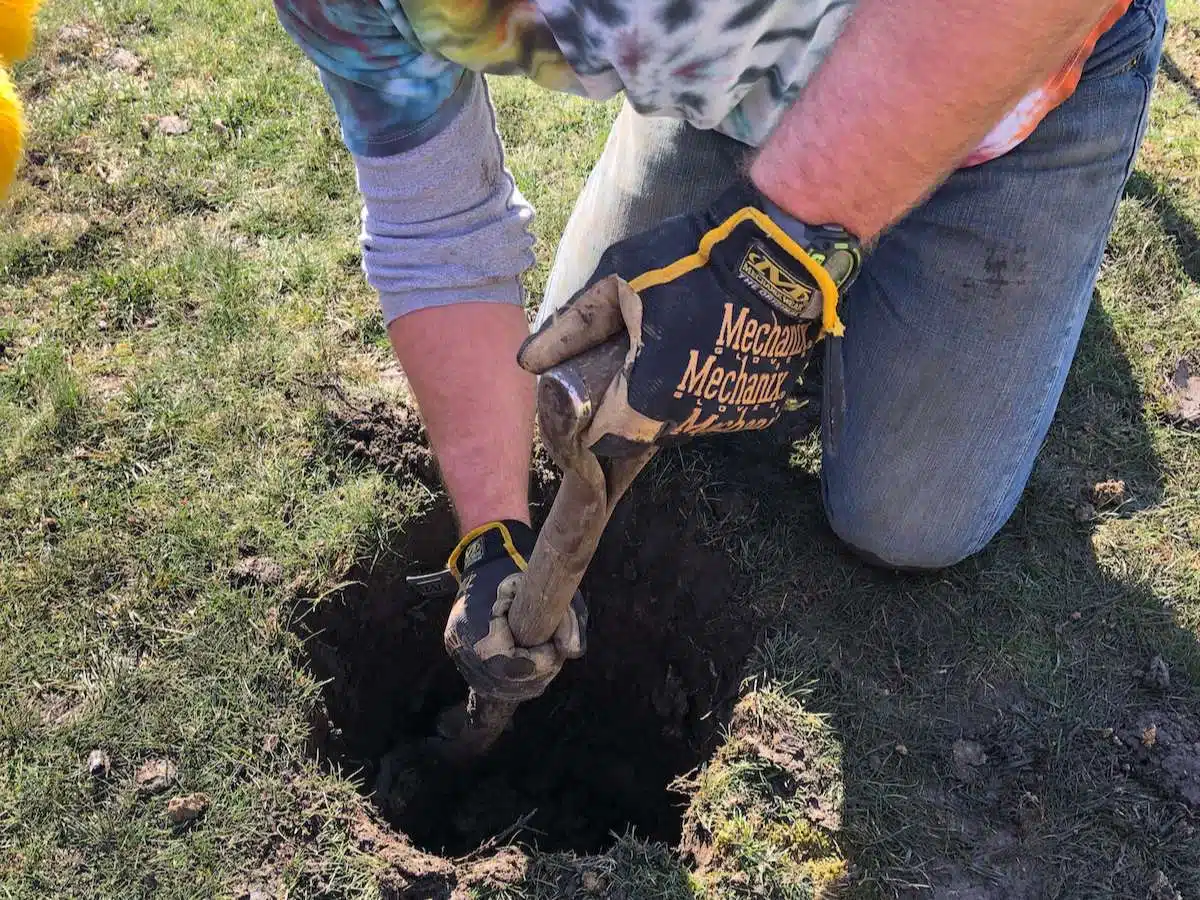 man digging hole for post to go in ground.