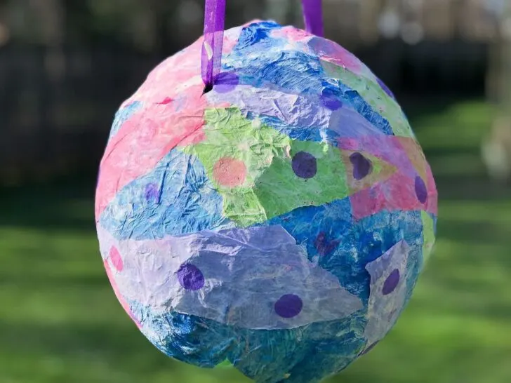 paper maché balloon piñata hanging outside.