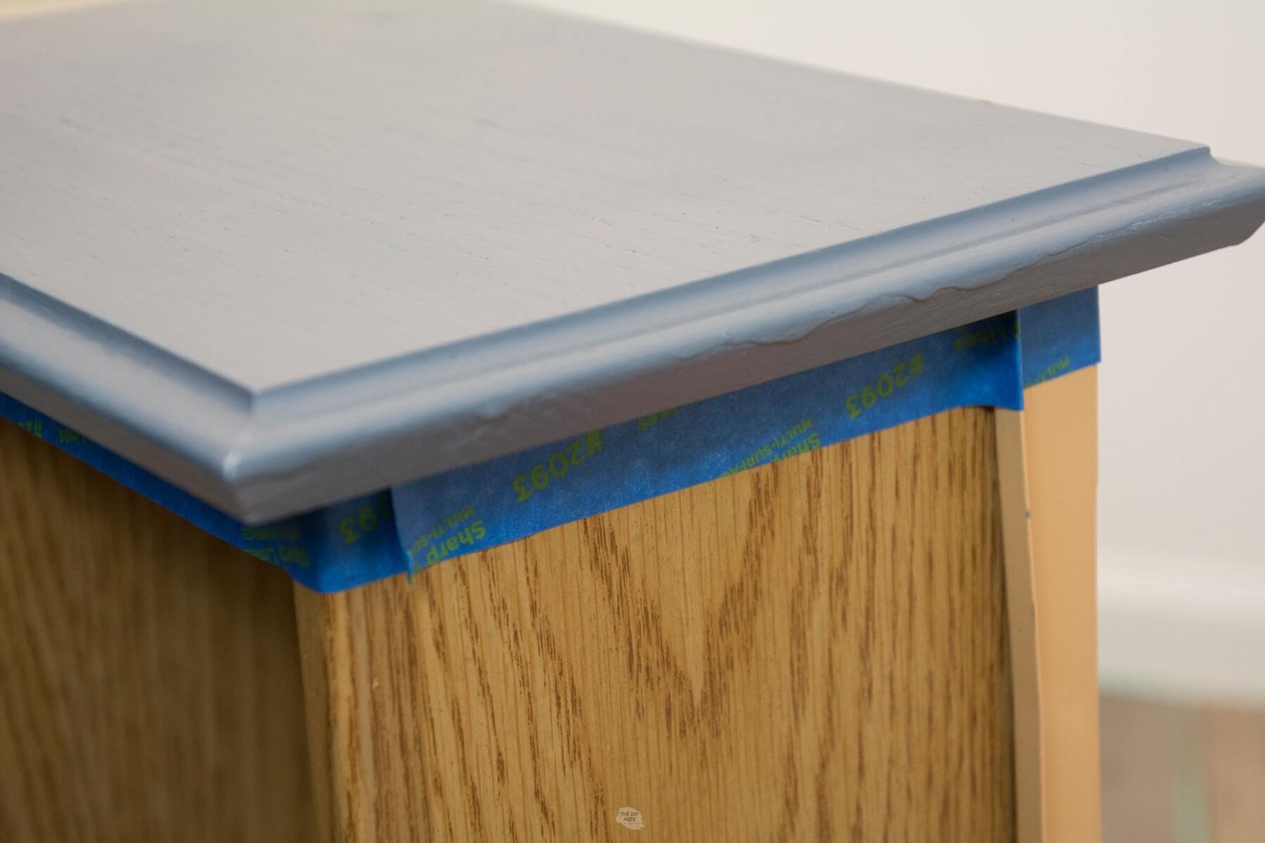 blue painter's tape around edges of painted cabinet drawer.