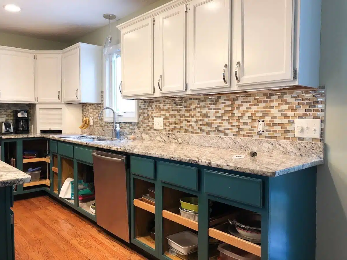 green painted lower cabinets with doors off, granite counters, glass backsplash and white upper painted cabinets in kitchen.