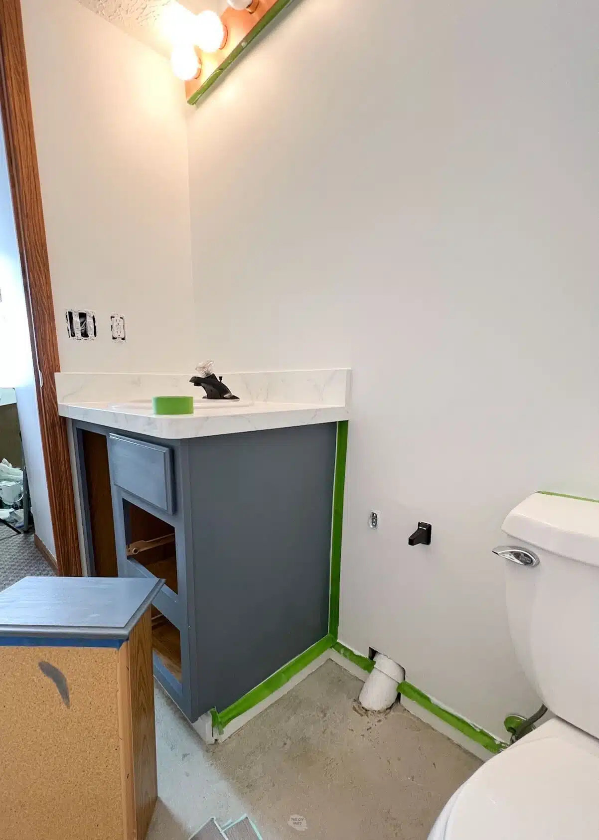 small bathroom with painted bathroom cabinets with green tape.