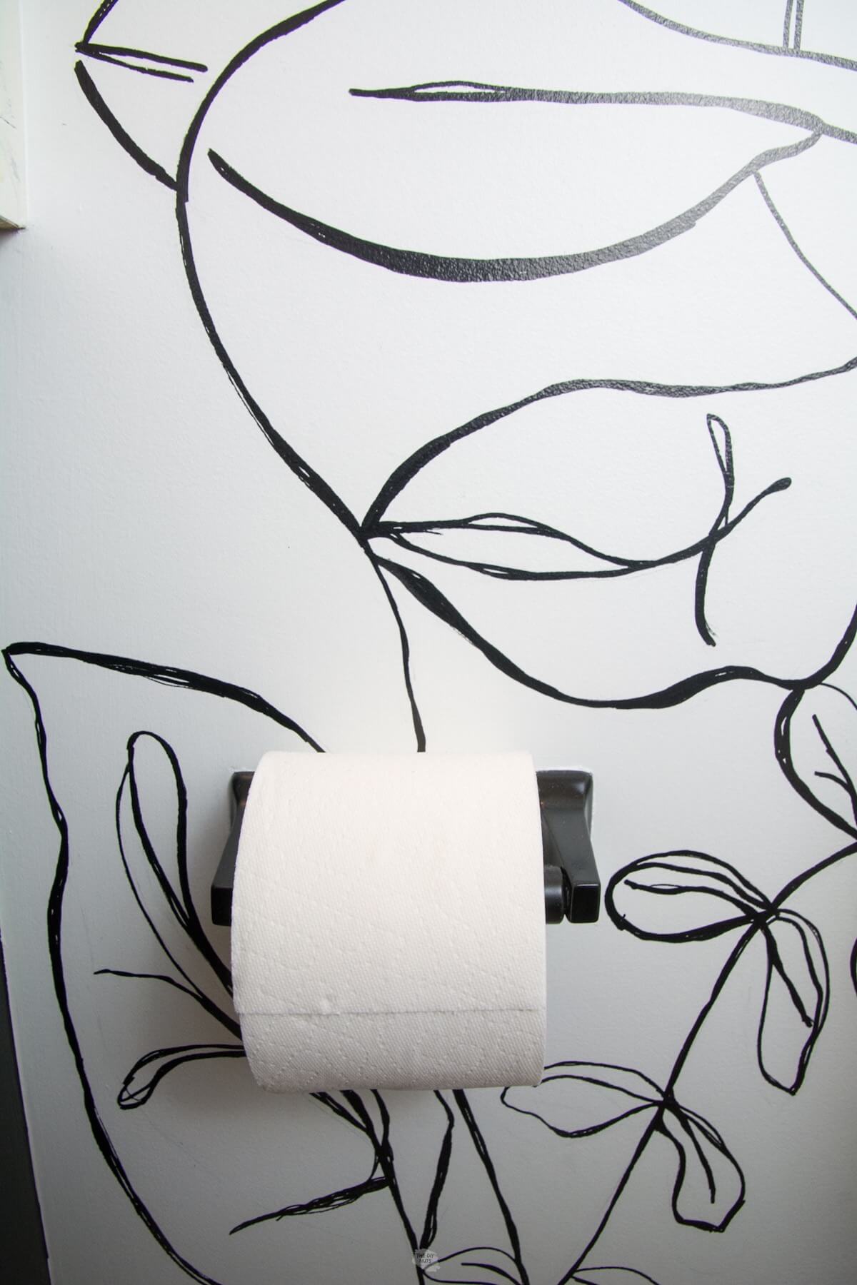 black spray painted toilet paper holder with black and white wall in the background.