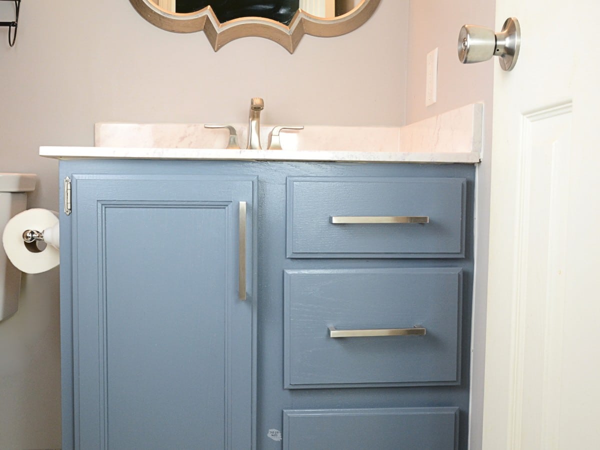 blue gray painted bathroom cabinet with silver handles and faucet.