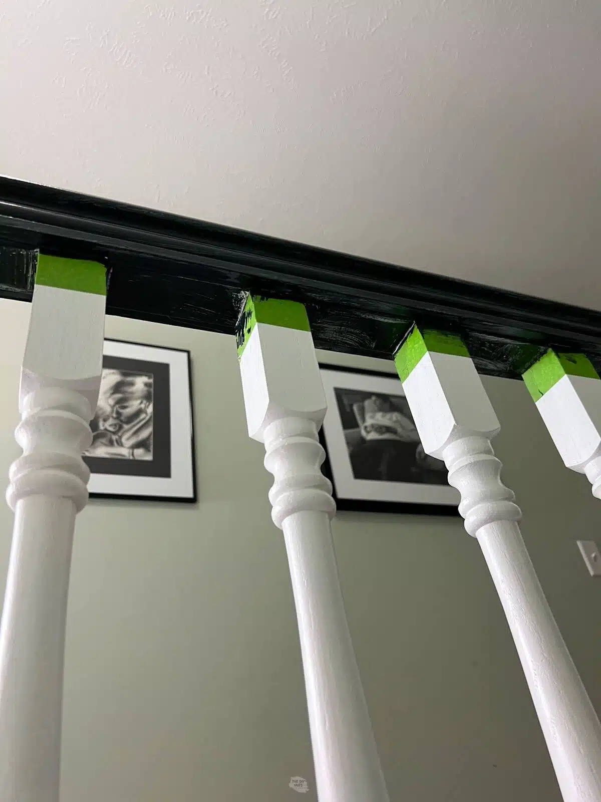 black painted handrail with white spindles and green tape.