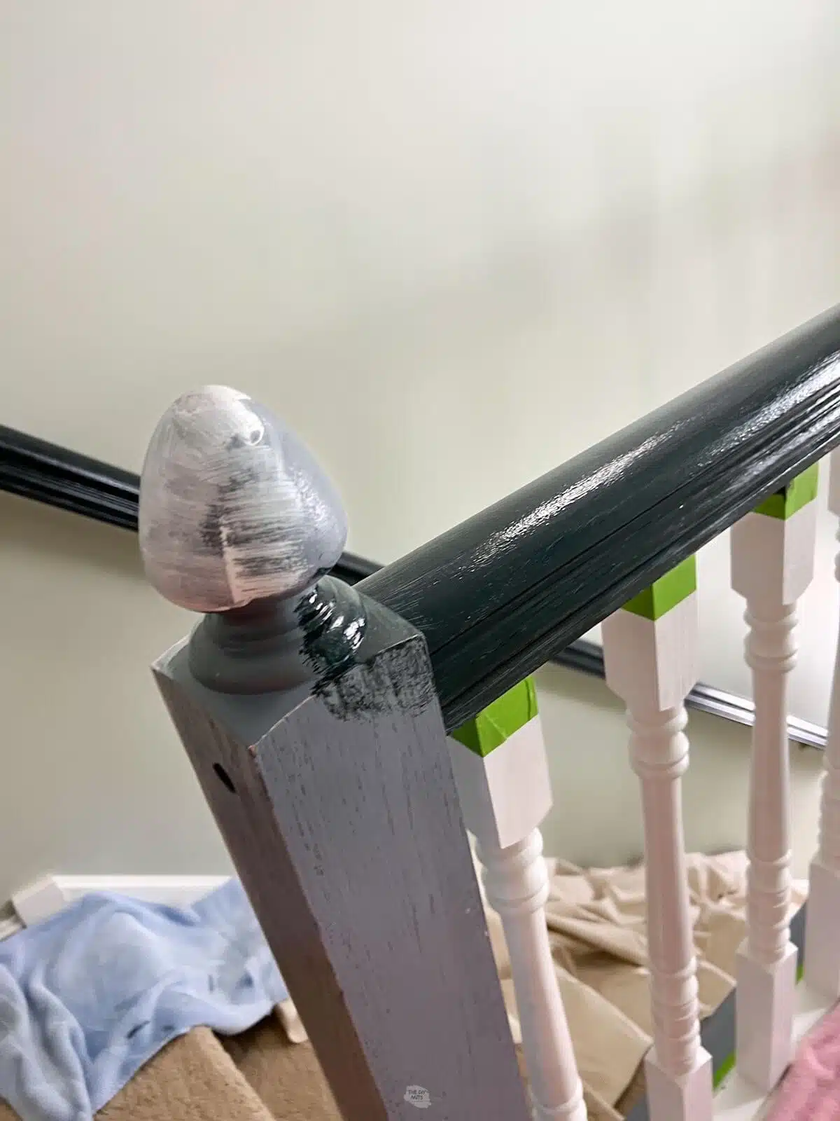 white primer on end of stair railing with other parts painted black, white and blue-gray.