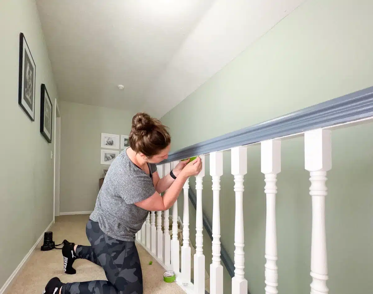 woman adding painter's tape around white painted spindles.