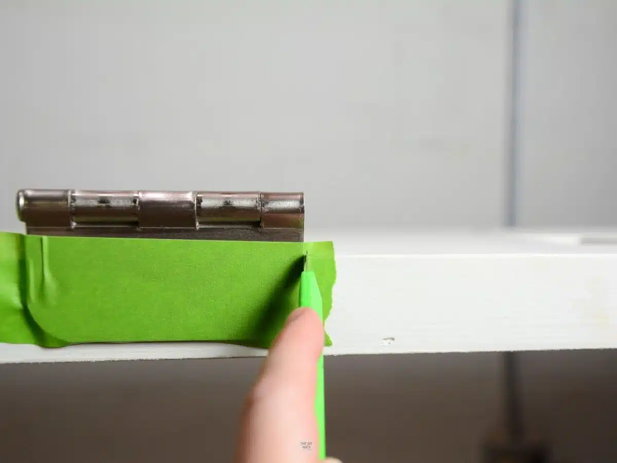 hand cutting green painter's tape on door hinge.