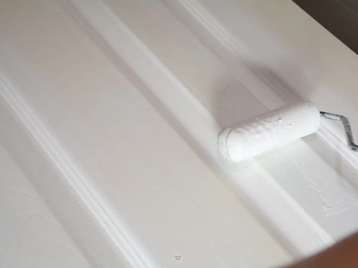 small foam roller applying white paint to interior door panel.