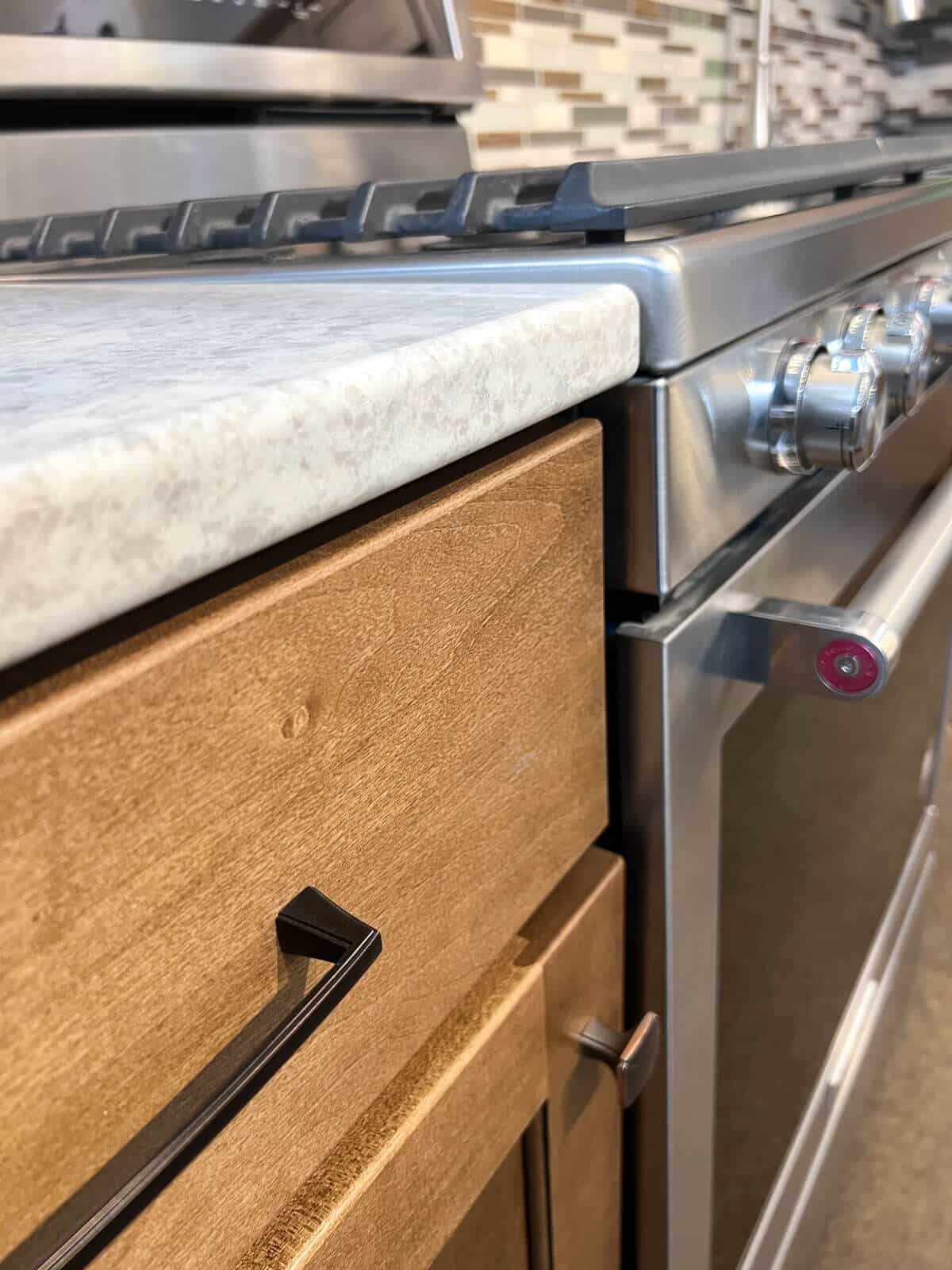 stainless steal oven with wood cabinets quartz countertop.