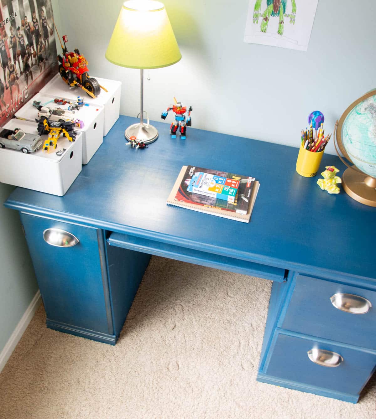blue chalked painted desk with legos, books and lamp on it.