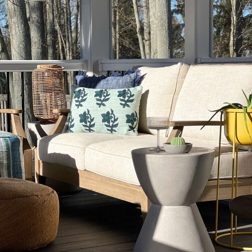 outdoor porch with couch and decorative outdoor pillows and side table.